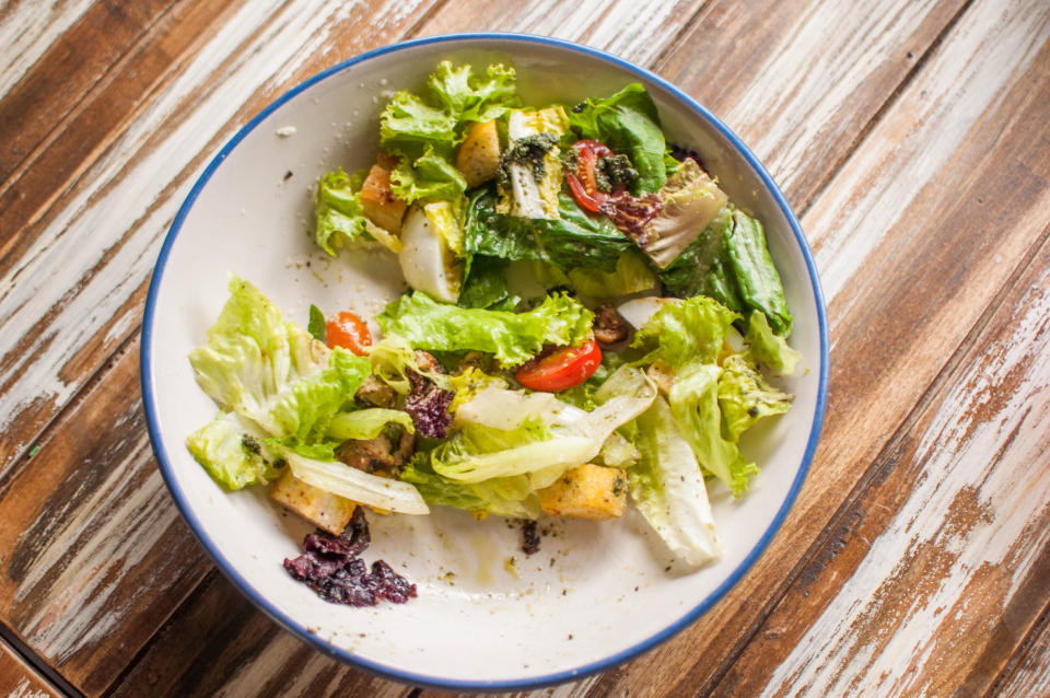 A high-angle view of green leafy salad bowl on a rustic wooden table