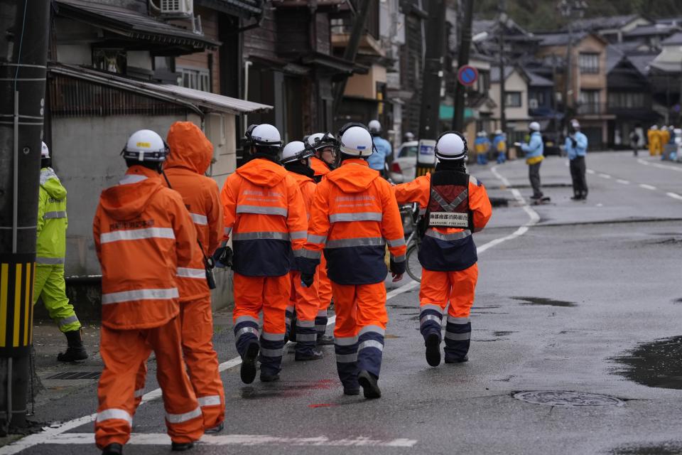 Firefighters advance though earthquake-damaged area in Wajima in the Noto peninsula facing the Sea of Japan, northwest of Tokyo, Sunday, Jan. 7, 2024. Monday's temblor decimated houses, twisted and scarred roads and scattered boats like toys in the waters, and prompted tsunami warnings. (AP Photo/Hiro Komae)