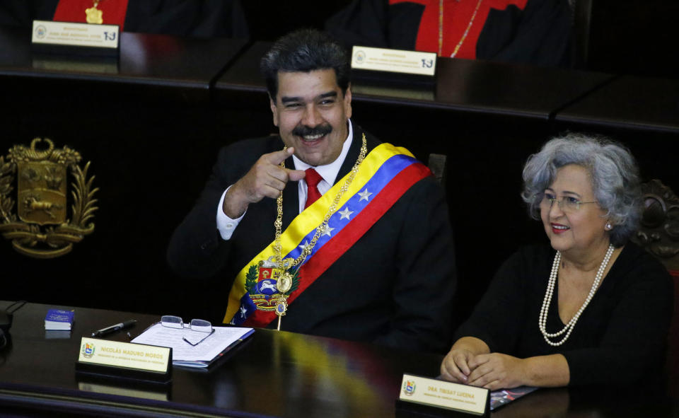 Venezuelan President Nicolas Maduro points to someone in the crowd as he sits inside the Supreme Court for an annual ceremony that marks the start of the judicial year in Caracas, Venezuela, Thursday, Jan. 24, 2019. At right is Tibisay Lucena, president of the National Electoral Council. Venezuelans are heading into uncharted political waters after the young leader of a newly united opposition claimed Wednesday to hold the presidency and Maduro dug in for a fight with the Trump administration. (AP Photo/Ariana Cubillos)