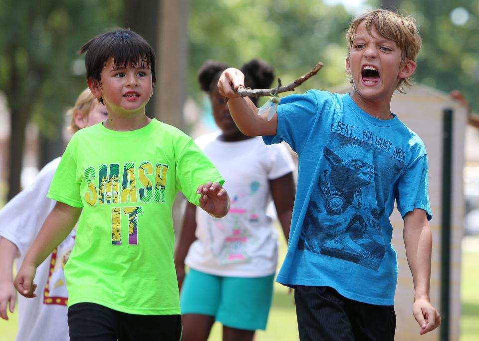 Caleb Miller, 9, right, carries a stick with a cicada on it as he and other children play at Monnish Park on an outing with Tuscaloosa Parks and Recreation Authority's summer day camp with the Phelps Center, in Tuscaloosa, Ala. on Tuesday, Aug. 11, 2015.  Staff photo | Erin Nelson