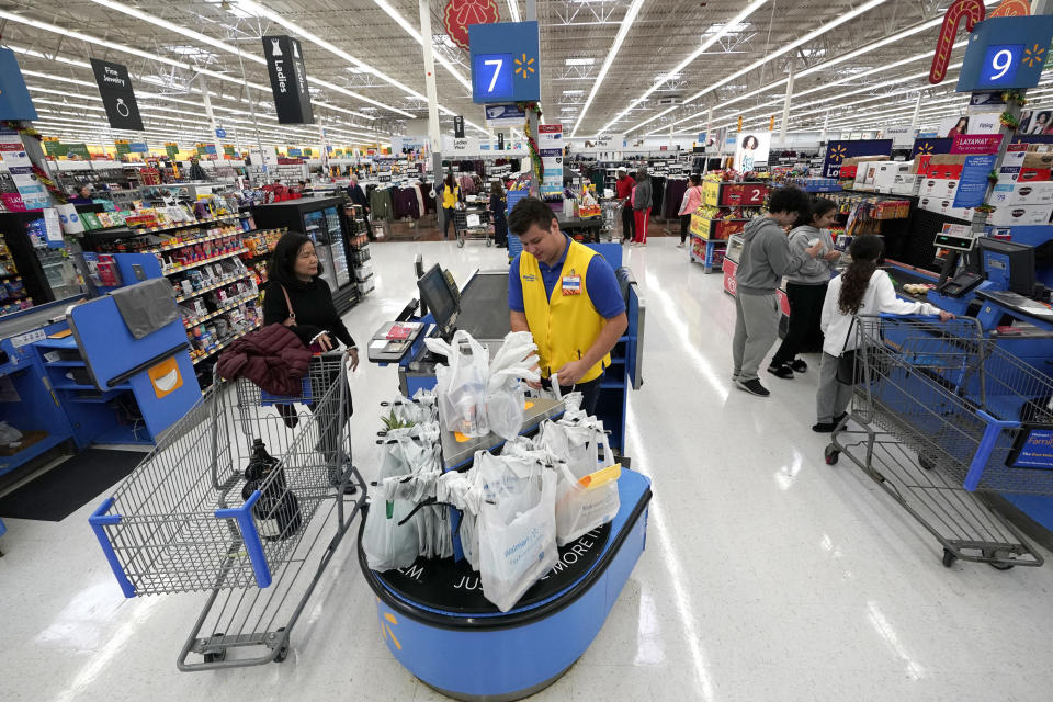 FILE- In this Nov. 9, 2018, file photo Walmart associate Luis Gutierrez, center, checks out a customer at a Walmart Supercenter in Houston. On Thursday, Jan. 31, 2019, the Labor Department releases the employment cost index for the fourth quarter, a measure of wage and benefit growth. (AP Photo/David J. Phillip, File)