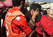 A Lebanese Red Cross worker, left, holds an injured Syrian man, Wessam Masri, 30, right, who was wounded by Syrian government forces shelling as he kissed by his mother, center, and goodbye him after he get ready to move to a hospital in central Lebanon, in Tfail village at the Lebanese-Syrian border, eastern Lebanon, Tuesday April 22, 2014. A Lebanese convoy of soldiers, clerics and Red Cross officials delivered aid Tuesday to a remote village near the Syrian border that was bombed by Syrian government aircraft and blocked by Lebanese militants fighting alongside President Bashar Assad’s forces in the civil war next door. Hezbollah fighters have been patrolling the area on the Lebanese side and fighting has flared up inside Syria, cutting Tfail’s residents off from all sides for months. (AP Photo/Hussein Malla)