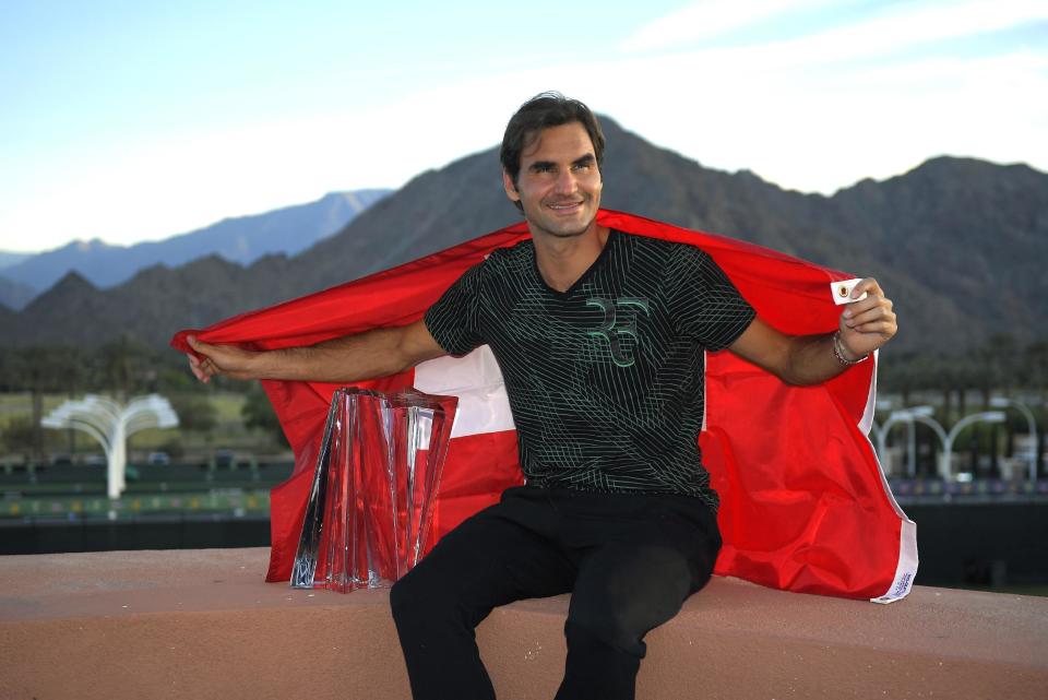 Roger Federer, of Switzerland, poses with his trophy and the Swiss flag after defeating Stan Wawrinka, also of Switzerland, in their final match at the BNP Paribas Open tennis tournament, Sunday, March 19, 2017, in Indian Wells, Calif. (AP Photo/Mark J. Terrill)