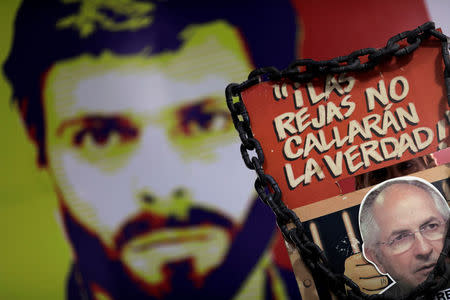 A man holds a sign with a portrait of opposition leader Antonio Ledezma in front of a wall with a portrait of opposition leader Leopoldo Lopez during a news conference at the Venezuelan coalition of opposition parties (MUD) headquarters in Caracas, Venezuela August 1, 2017. The sign reads "The bars will not shut the truth". REUTERS/Ueslei Marcelino