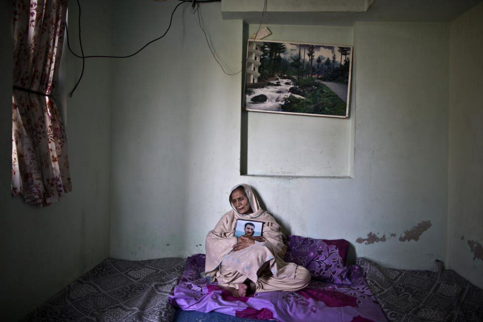 In this Sunday, March 16, 2014 photo, Pakistani Marouf Jaan Ali, 69, mother of cleric Kamran Ali, 27, who was one of eleven victims that was killed by suicide bombers in an attack on a court complex on the 3rd of March 2014, grieves while embracing his photograph in his bedroom, in Rawalpindi, Pakistan. "I miss him kissing my forehead before he leaves and after he comes back home from work," Marouf said. (AP Photo/Muhammed Muheisen)