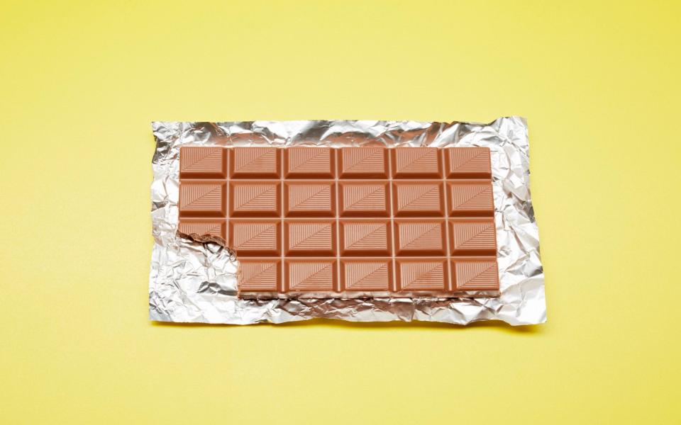 High angle view of chocolate bar on foil and yellow background