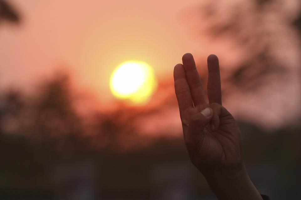 A protesters flashes the three-fingered protest sign during a march in Mandalay, Myanmar, at sunset on Monday, Feb. 8, 2021. Tension in the confrontations between the authorities and demonstrators against last week's coup in Myanmar boiled over Monday, as police fired a water cannon at peaceful protesters in the capital Naypyitaw. (AP Photo)