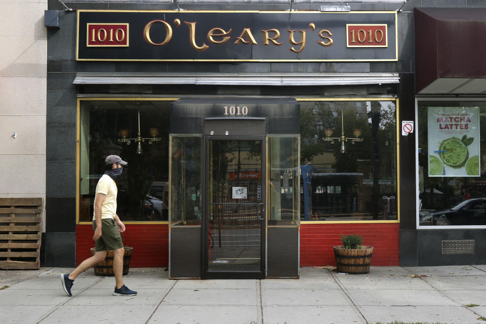 A pedestrian passes by O'Leary's Irish Pub, Tuesday, Aug. 4, 2020, in Brookline, Mass. After being in business for nearly three decades, the pub permanently closed during the coronavirus pandemic. (AP Photo/Bill Sikes)