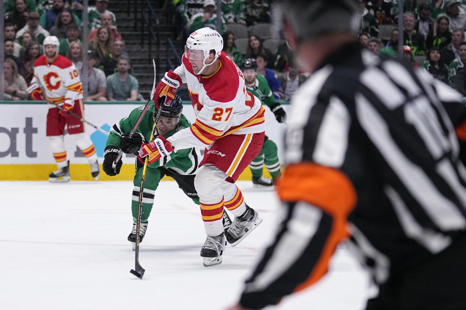 Calgary Flames left wing Nick Ritchie (27) shoots as Dallas Stars' Max Domi, front left, defends in the second period of an NHL hockey game, Monday, March 6, 2023, in Dallas. (AP Photo/Tony Gutierrez)