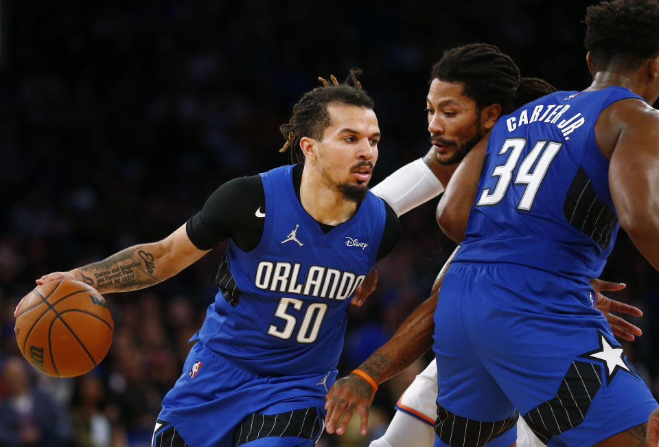 Orlando Magic's Cole Anthony (50) dribbles around teammate Wendell Carter Jr. (34) as New York Knicks' Derrick Rose (4) defends during an NBA basketball game Sunday, Oct. 24, 2021, in New York. (AP Photo/John Munson)