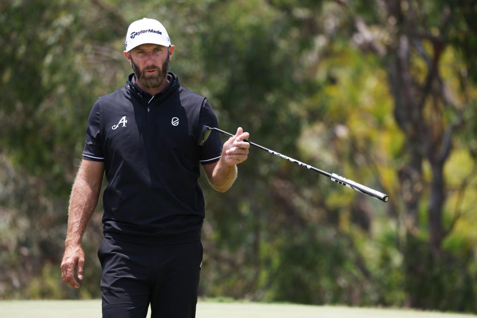 Dustin Johnson hands his putter to his caddie