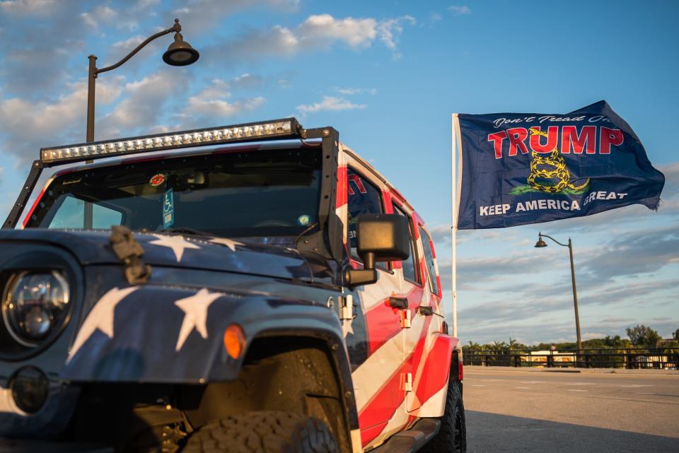 A flag decorated with the name of former President Donald Trump waves in the wind attached to a stars-and-stripes decorated vehicle parked on the bridge portion of Southern Boulevard leading to Mar-A-Lago, the former president's residence on Thursday, March 30, 2023, in Palm Beach, FL. On Thursday, a grand jury in Manhattan voted to indict Trump in connection with an alleged payment of hush money to adult actress Stormy Daniels in 2016. 