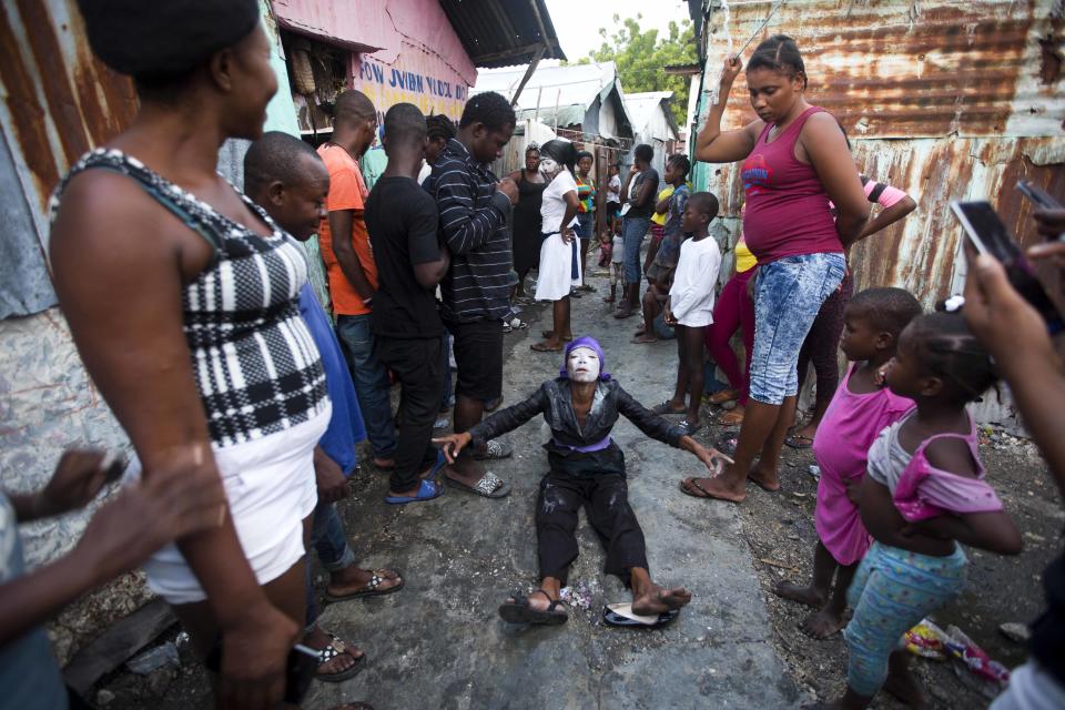 In this Nov. 1, 2018 photo, a voodoo believer who is supposed to be possessed with a Gede spirit, performs rituals near Baron Samedi's tomb during the annual Voodoo festival Fete Gede at Cite Soleil Cemetery in Port-au-Prince, Haiti. The characteristics of this traditional celebration, the flamboyant customes and the white-powdered faces of the priests in trance inspired some of the first Hollywood stories about zombies. ( AP Photo/Dieu Nalio Chery)