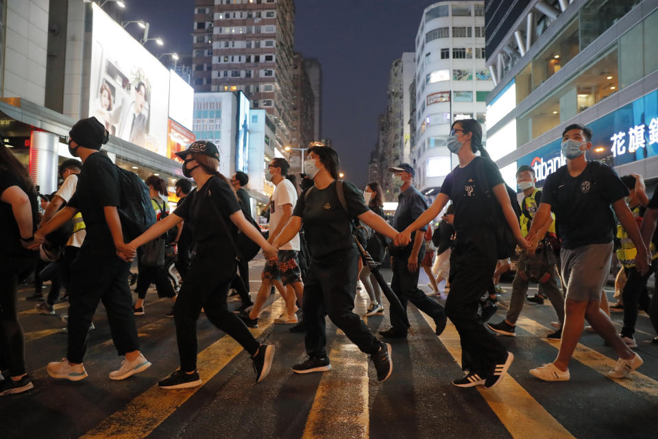 Masked protesters hold hands to form a human chain to protest against the ban on masks in Hong Kong, Saturday, Oct. 5, 2019. All subway and train services were suspended, lines formed at the cash machines of shuttered banks, and shops were closed as Hong Kong dusted itself off and then started marching again Saturday after another night of rampaging violence decried as "a very dark day" by the territory's embattled leader. (AP Photo/Kin Cheung)