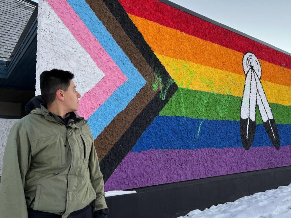 Yax Posas, president of the Gay and Lesbian Association of the Peace, looks at a vandalized pride flag mural that was originally painted by the group in 2021. (Luke Ettinger/CBC - image credit)