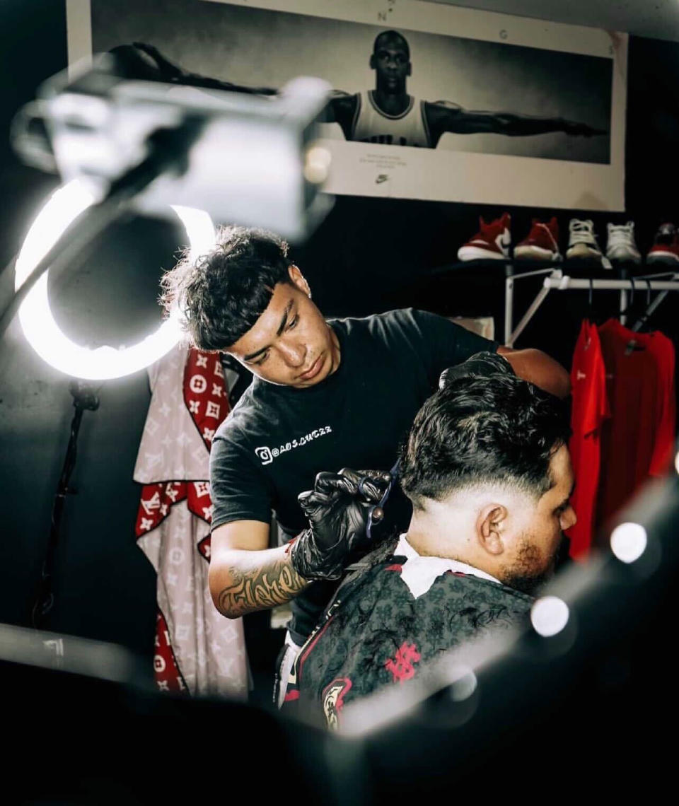 Image: Carlos Flores, a barber, cuts the hair of another man. (Courtesy Giovanni Mondragon)