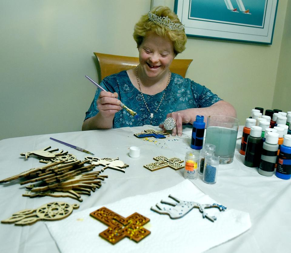 Leslie Larkins, proudly wearing her tiara, enjoys crafts as she paints wooden crosses, reindeer and an assortment of Christmas pieces that she passed out to her extended family at Thanksgiving.