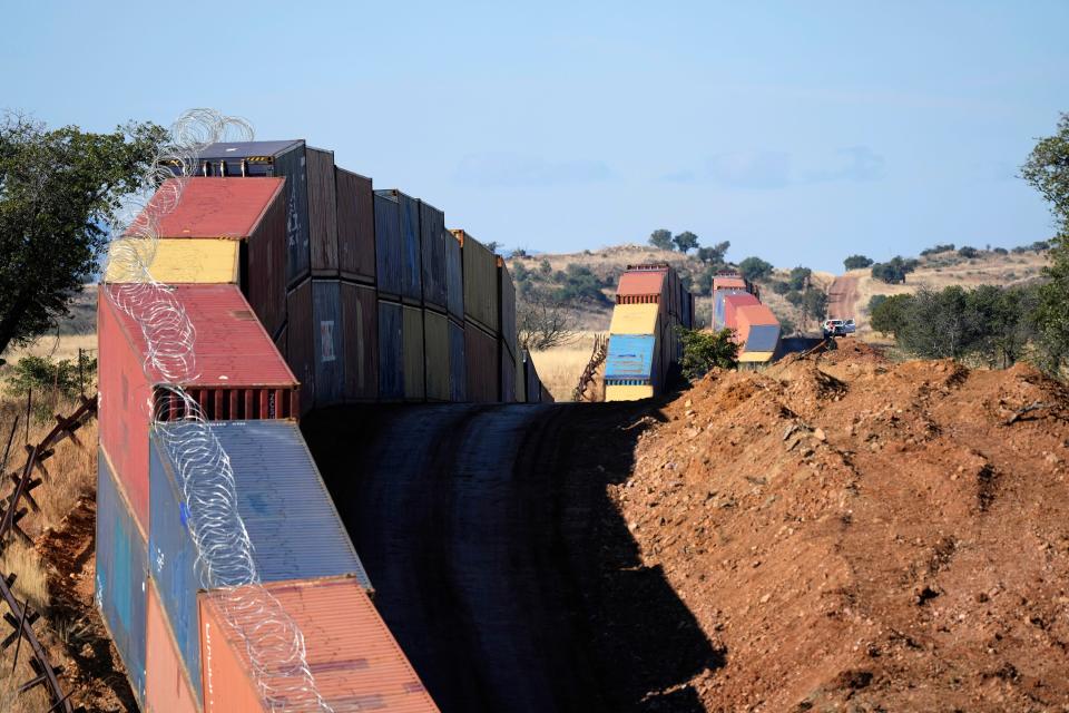 A long row of double-stacked shipping containers provide a new wall between the United States and Mexico in the remote section area of San Rafael Valley, Ariz., Thursday, Dec. 8, 2022. Work crews are steadily erecting hundreds of double-stacked shipping containers along the rugged east end of Arizona’s boundary with Mexico as Republican Gov. Doug Ducey makes a bold show of border enforcement even as he prepares to step aside next month for Democratic Governor-elect Katie Hobbs.