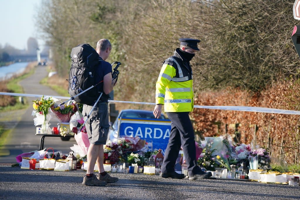 A Garda talks to a rambler by the floral tributes laid at the Grand Canal in Tullamore, Co Offaly (Niall Carson/PA) (PA Wire)