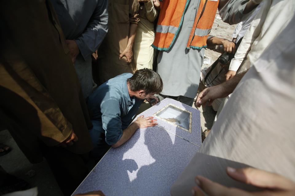 Man cries over coffin of his brother, who was killed in a bomb blast, at a hospital in Peshawar