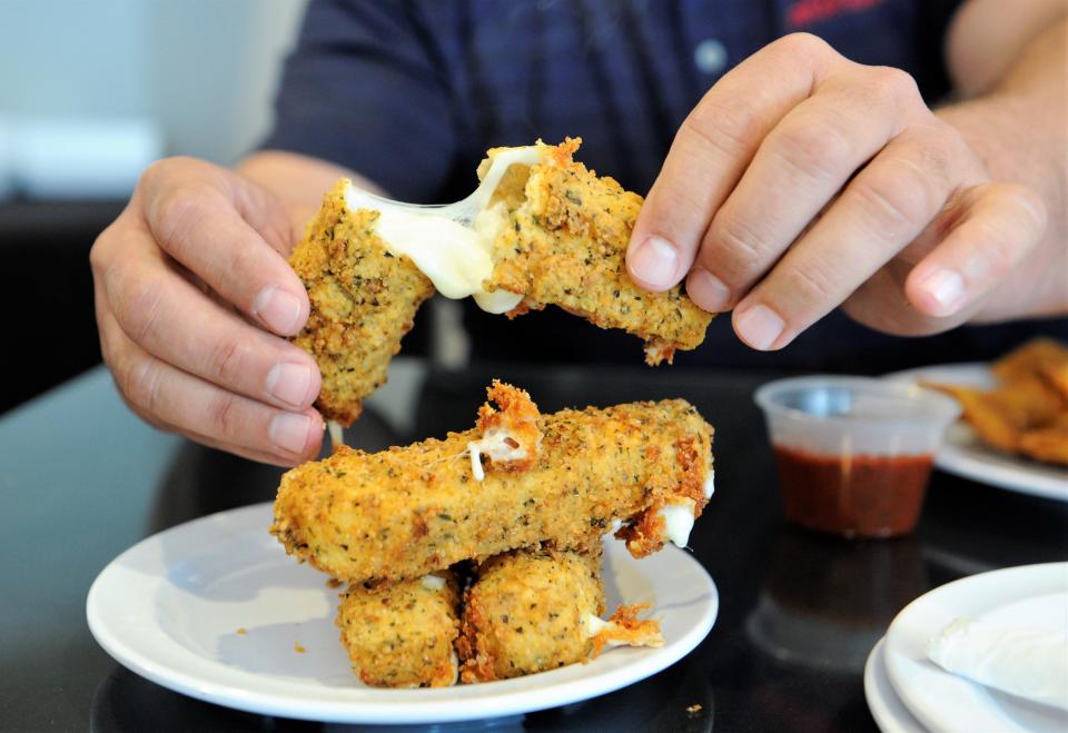 A diner digs into an order of Cheese Twinkies at Dontae's on Main Pizza Parlor on Thursday, June 10, 2021. The locally famous appetizer will be on the menu at Kipplee's Pizza for a limited time.