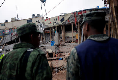 Soldiers stand near parts of a collapsed school building during a search for students at the Enrique Rebsamen school after an earthquake in Mexico City, Mexico, September 21, 2017. REUTERS/Daniel Becerril