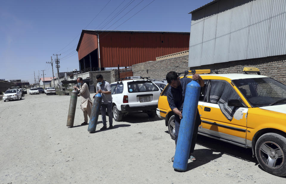 Men carry cylinders to be refilled from a privately owned oxygen factory, in Kabul, Afghanistan, Saturday, June 19, 2021. Health officials say Afghanistan is fast running out of oxygen as a deadly third surge of COVID worsen. (AP Photo/Rahmat Gul)