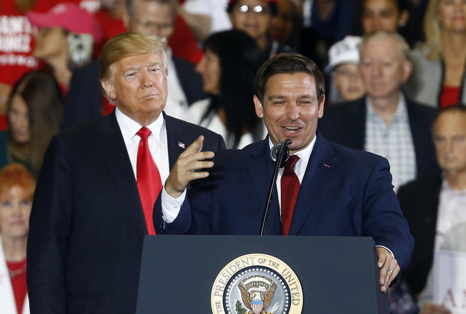 FILE- In this Nov. 3, 2018 file photo President Donald Trump stands behind gubernatorial candidate Ron DeSantis at a rally in Pensacola, Fla. Republican former U.S. Rep. Ron DeSantis is facing Democratic Tallahassee Mayor Andrew Gillum in one of the closest watched and improbable governor races in the country. (AP Photo/Butch Dill, File)