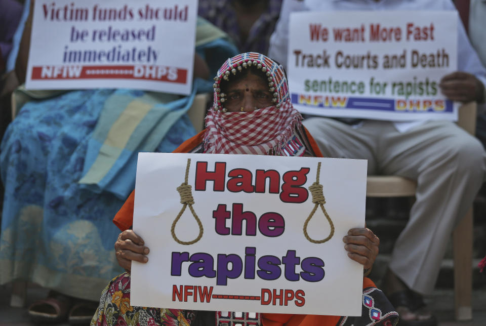 An activist with her face covered as a precautionary measure against the coronavirus holds a placard during a protest against the gang rape and killing of a woman in India's northern state of Uttar Pradesh, in Hyderabad, India, Friday, Oct. 2, 2020. The gang rape and killing of the woman from the lowest rung of India's caste system has sparked outrage across the country with several politicians and activists demanding justice and protesters rallying on the streets. (AP Photo/Mahesh Kumar A.)