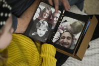 Estella Baraniak, 8, sits with her grandfather Brian Baraniak and looks at a family photo album with images of her deceased father, Matthew Baraniak, in Halifax, Pa., Wednesday, March 6, 2024. Matthew Baraniak was on work release in 2019 when he was killed at a Pennsylvania heavy machinery service center while operating a scissor lift.(AP Photo/Matt Rourke)