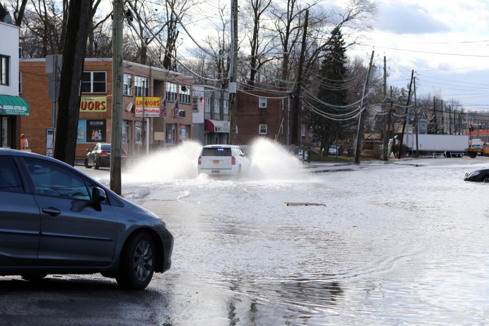 A motorist drives through a closed off area due to flooding on Route 9A in Elmsford Jan. 10, 2024. A stretch of business along the route are closed because of flooding after last night's storm.