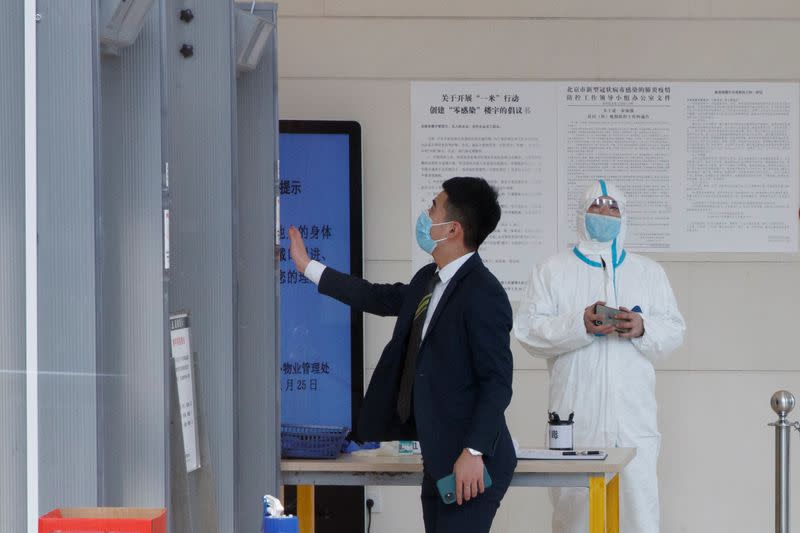 A worker wears a protective suit as a businessman enters an office building in Beijing as the country is hit by an outbreak of the novel coronavirus