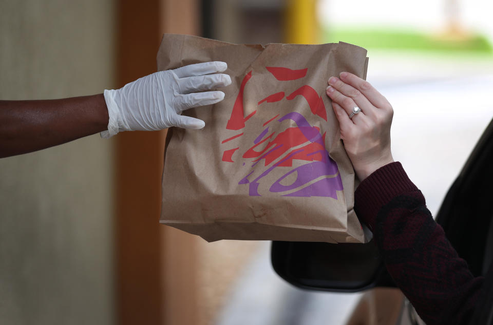 HOLLYWOOD, FLORIDA  - MARCH 31: A Taco Bell employee delivers an order to a customer at the drive-up window of the restaurant on March 31, 2020 in Hollywood, Florida.  Mark King, CEO of Taco Bell Corp. announced that Tuesday, March 31, Taco Bell drive-thru guests across America will receive a free seasoned beef Nacho Cheese Doritos Locos Tacos, no purchase necessary while supplies last as part of its coronavirus response. (Photo by Joe Raedle/Getty Images)