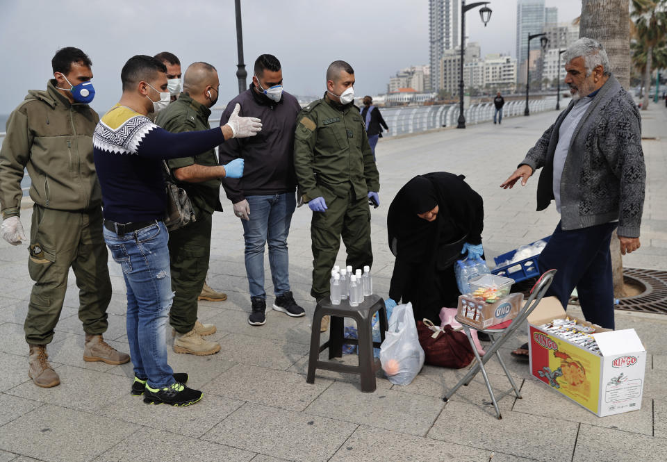 CAPTION CORRECTION:CORRECTS BYLINE - Municipal policemen, left, order street vendors to leave the corniche, or waterfront promenade, along the Mediterranean Sea, as the country's top security council and the government were meeting over the spread of coronavirus, in Beirut, Lebanon, Sunday, March 15, 2020. Lebanon has been boosting precautionary measures including halting flights from several countries, closing all restaurants and nightclubs and tightening measures along the border with neighboring Syria. (AP Photo/Hussein Malla)