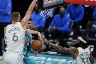 Charlotte Hornets guard LaMelo Ball passes the ball between Dallas Mavericks' Kristaps Porzingis, left, and Willie Cauley-Stein during the first half of an NBA basketball game in Charlotte, N.C., Wednesday, Jan. 13, 2021. (AP Photo/Chris Carlson)