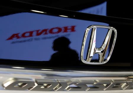 A visitor and a logo of Honda Motor are reflected on a Honda Odyssey car at the company showroom in Tokyo July 29, 2014. REUTERS/Toru Hanai