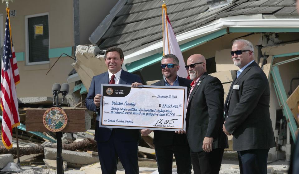 Gov. Ron DeSantis hands a check to, from left, Volusia County councilmen Danny Robins and Matt Reinhart and County Manager George Recktenwald on Wednesday, Jan. 18, 2023, on the beach ramp at Dunlawton and Atlantic avenues in Daytona Beach Shores.