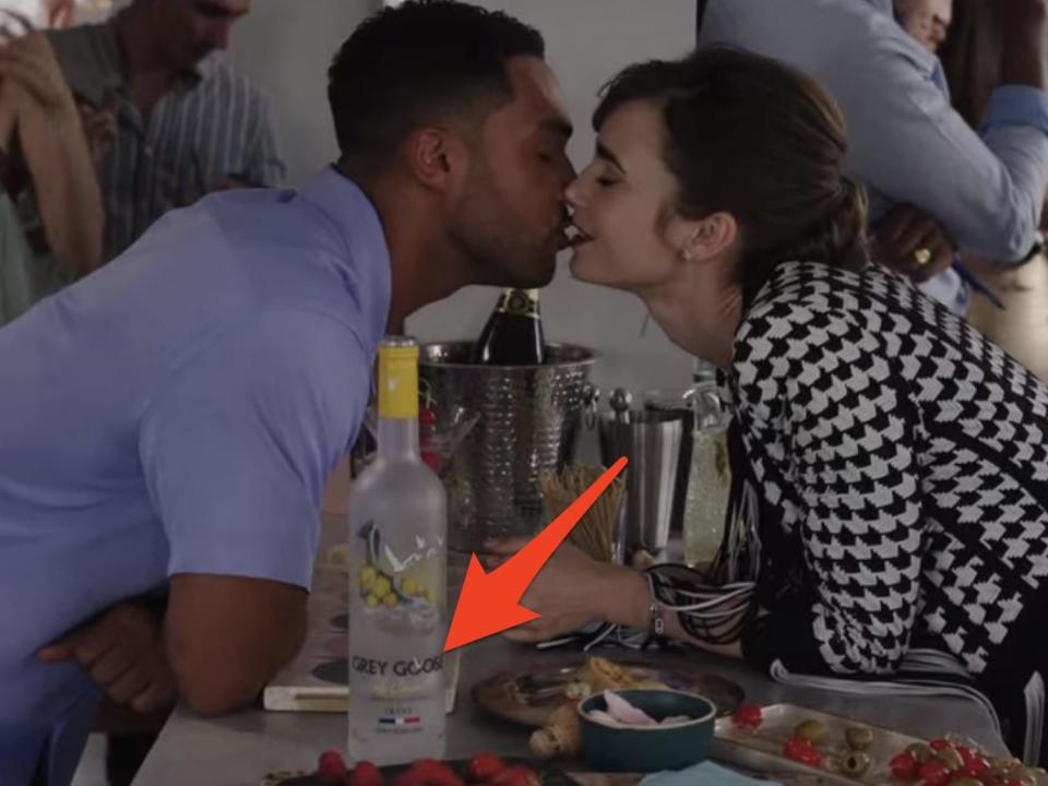 emily and alfie kissing near a bottle of grey goose at alfie's party on emily in paris season three episode five