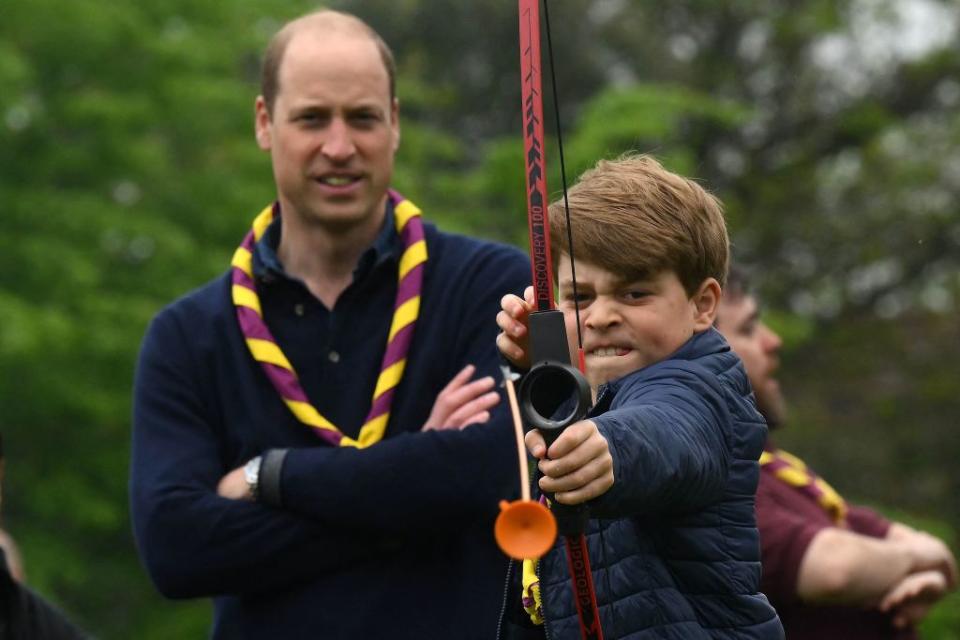 Watched by his father Britain's Prince William, Prince of Wales, Britain's Prince George of Wales tries his hand at archery while taking part in the Big Help Out, during a visit to the 3rd Upton Scouts Hut in Slough, west of London on May 8, 2023