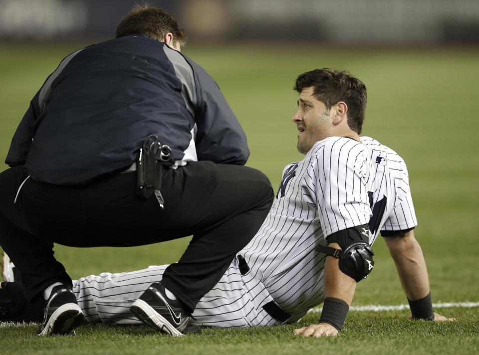 A Yankees trainer, left, talks to New York Yankees Francisco Cervelli who was injured on a fourth-inning force out play that was overturned in a baseball game against the Boston Red Sox at Yankee Stadium in New York, Sunday, April 13, 2014. The Yankees Brian McCann scored on the play, but Cervelli left the game. (AP Photo/Kathy Willens)