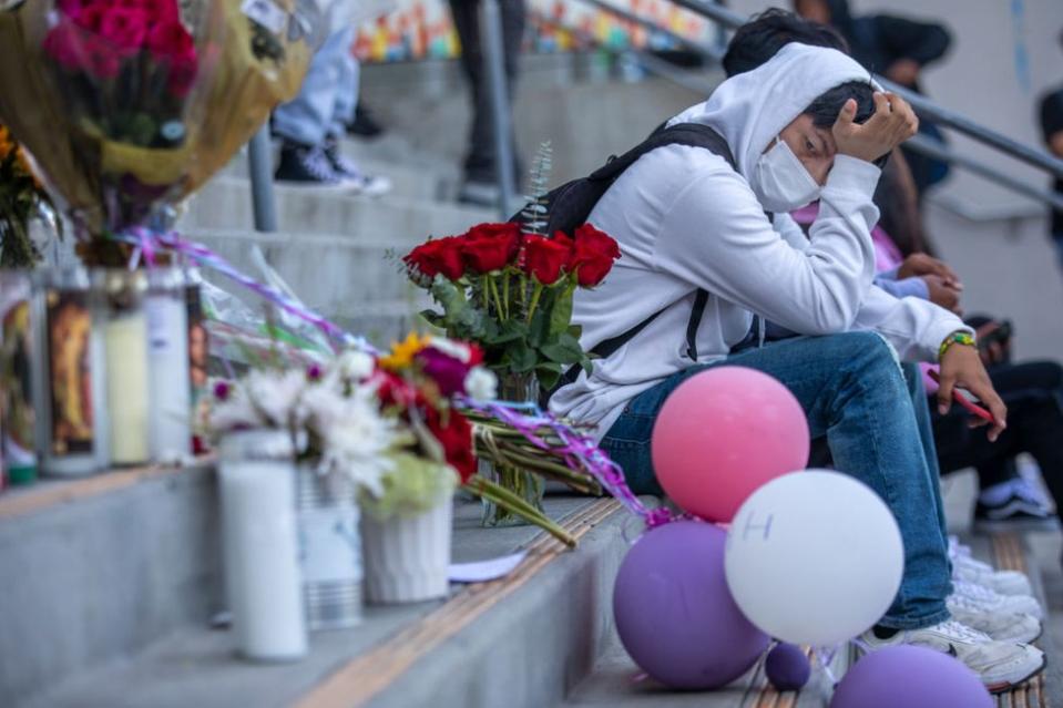 Johann Hervert, de 18 años, sentado junto a unas flores, globos y ofrendas colocadas en las escaleras del la secundaria Helen Bernstein de Hollywwod, Los Ángeles, en memoria de Melanie Ramos, alumna del centro fallecida por sobredosis de fentanilo. Foto del 16 de septiembre de 2022.