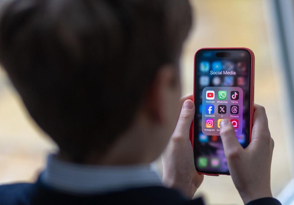 Kid holds phone with social media icons on screen