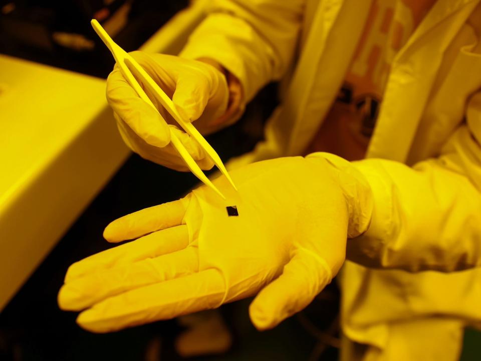 Hand holds a tiny chip being tested in a lab