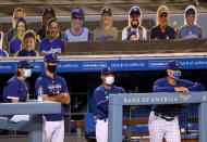 <p>Bob Geren #8, Manager Dave Roberts #30, Mark Prior #23 and Danny Lehmann watch the final out of the game in front of cutout fan faces, in 12-2 preseason win over the Arizona Diamondbacks during the COVID-19 pandemic at Dodger Stadium on July 20.</p>