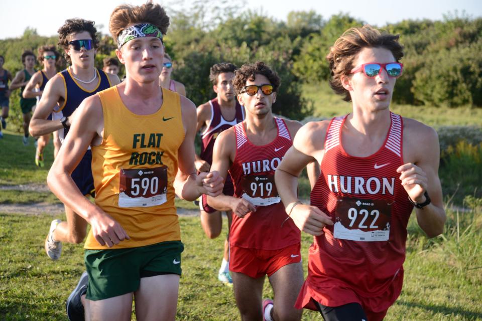 Nathan Vargo of Flat Rock (590) runs with the New Boston Huron duo of Lucas Kuhn (922) and Abdul Ghennewa (919) in the Huron League cross country jamboree at Sterling State Park Tuesday.