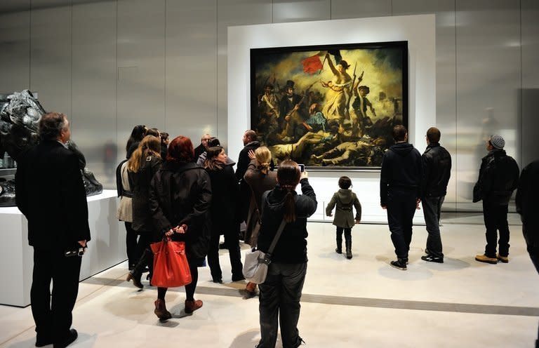 People stand in front of Eugene Delacroix's masterpiece "Liberty Leading the People" on display in Lens, northern France, on December 4, 2012. One of the most iconic paintings in French history, Delacroix's "Liberty Leading the People", has been defaced by a woman allegedly suffering psychiatric problems, but no permanent damage was done