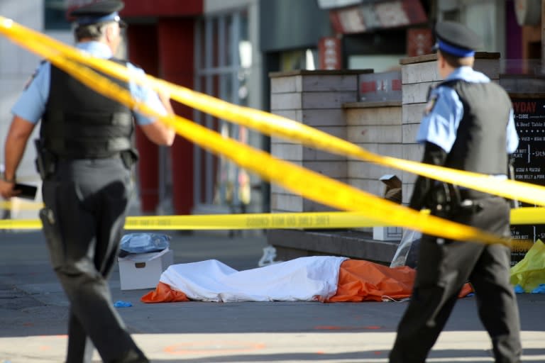 Police officers stand near one of the bodies of the victims in downtown Toronto