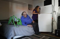 In this Oct. 12, 2018, photo, Celeste Mills loads food into a refrigerator as Gordon Lamb at their room in a weekly rental motel in Reno, Nev. "There's not much choice," said Mills about being unable to afford a regular apartment, "First month, last month, and security deposit are just too much." (AP Photo/John Locher)