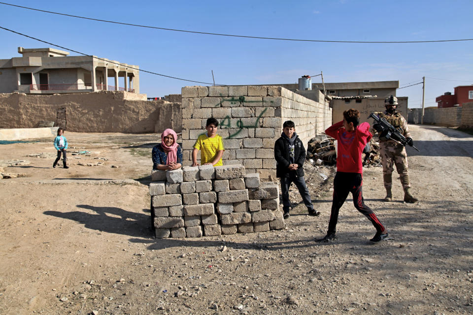 Local Yazidis stand outside their homes in the village of Tal Binat, Sinjar, Iraq, Friday, Dec. 4, 2020. A new agreement aims to bring order to Iraq's northern region of Sinjar, home to the Yazidi religious minority brutalized by the Islamic State group. Since IS's fall, a tangled web of militia forces have run the area, near the Syrian border. Now their flags are coming down, and the Iraqi military has deployed in Sinjar for the first time in nearly 20 years. (AP Photo/Samya Kullab).