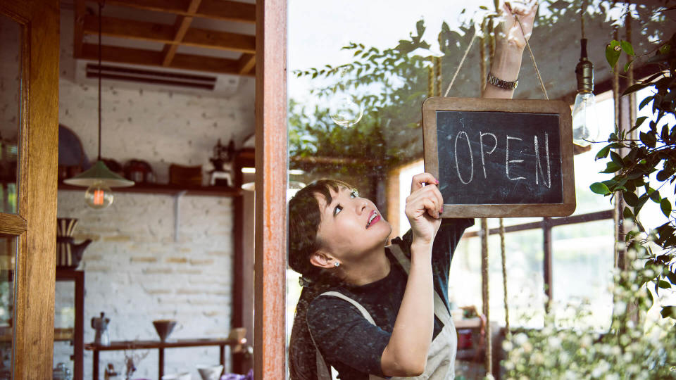 Woman hanging an open sign.